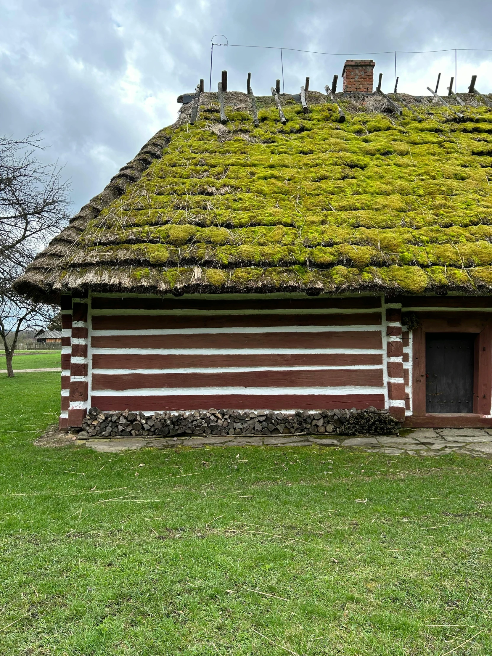 an old log cabin with grass on top