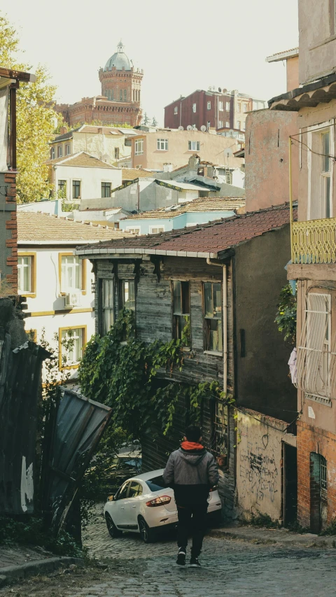 a person with an umbrella walks down a cobblestone street