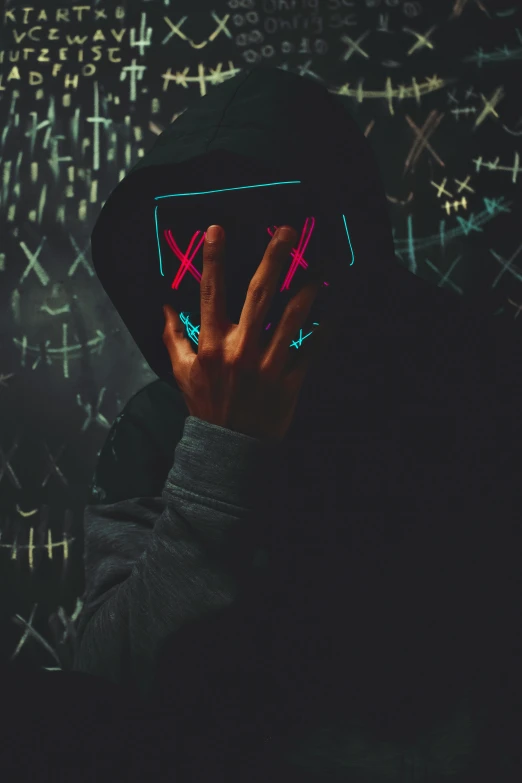 person wearing black hooded jacket and neon hand sign