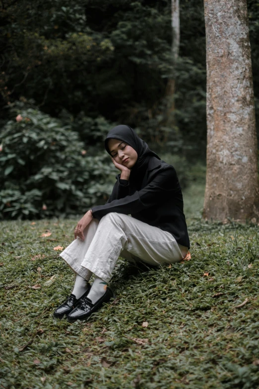 woman sitting in grassy area with trees and green vegetation