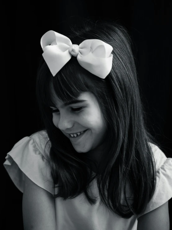 the girl smiles while wearing a bow around her hair