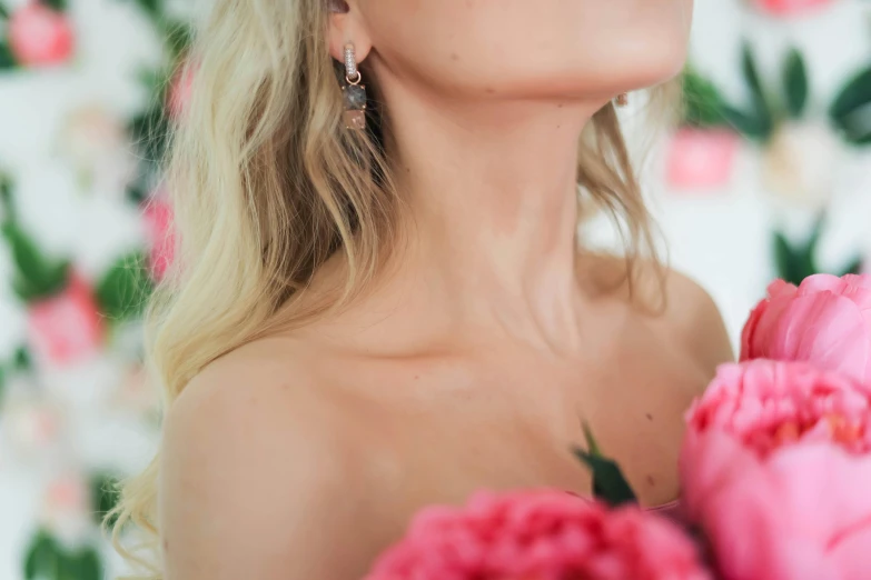 a young blonde woman with earrings on holding a flower