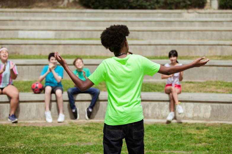 four children sitting on concrete benches watching other people play soccer