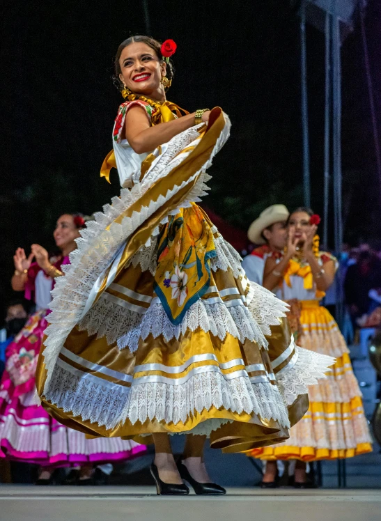 a woman is dancing outside at night, wearing an elaborate dress