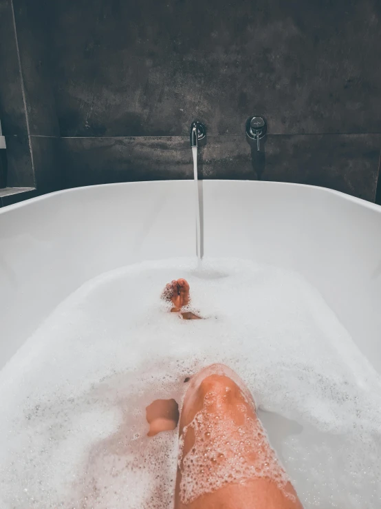 the feet are inside of a tub filled with water
