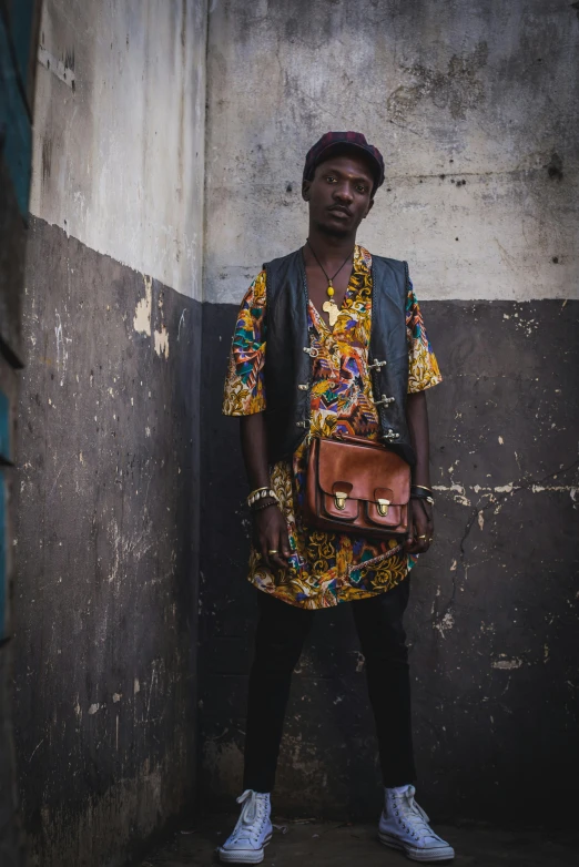 a man standing against an old wall holding his purse