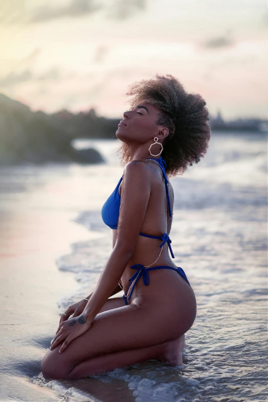 a woman in a blue bikini is sitting down on the beach