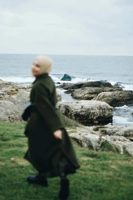 a person standing in the grass near the ocean