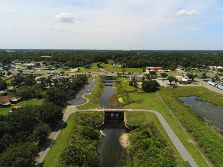 the aerial view shows a bridge over a body of water and many green fields