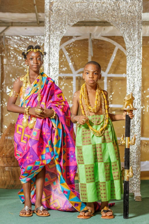 two young women with large gold necklaces in front of a stage