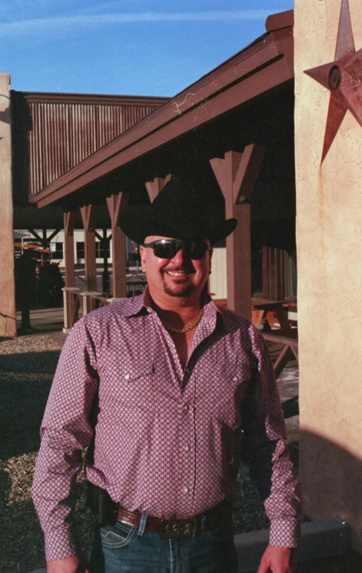 a smiling man wearing a cowboy hat and sunglasses