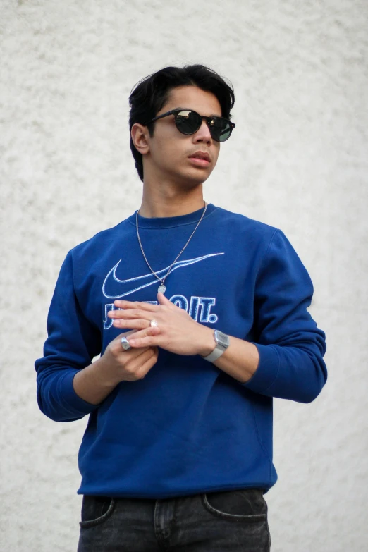 an asian man is wearing a blue sweater and sunglasses