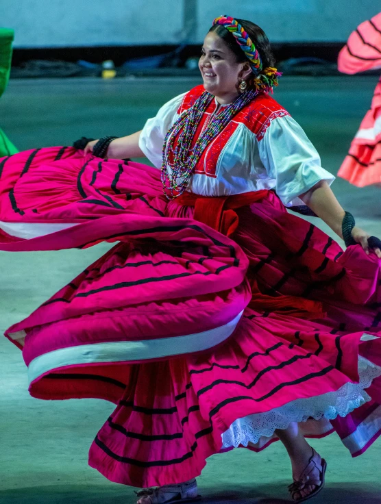 an older woman in a mexican dress dancing with two parasols