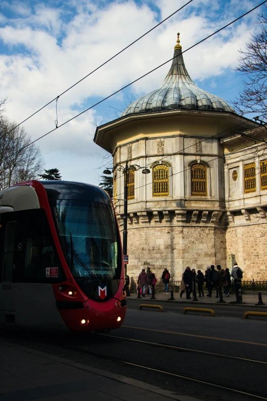 a red tram driving by an old building