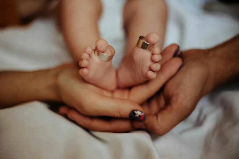 a woman and a baby holding hands on a bed