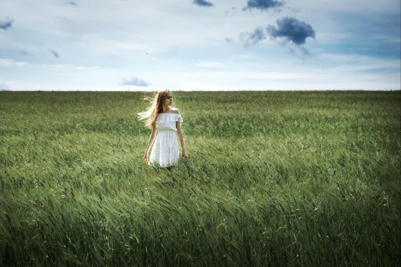 a woman in a field with her hair blowing in the wind