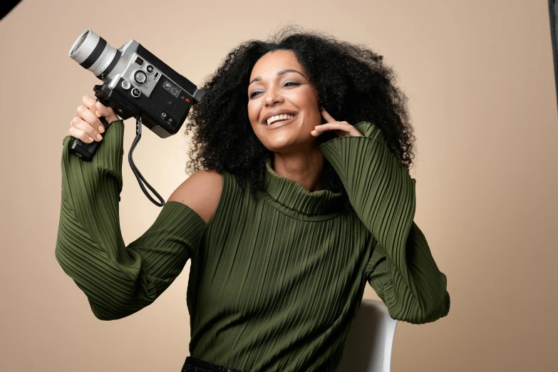 a woman sitting in a chair with a hair dryer and smiling