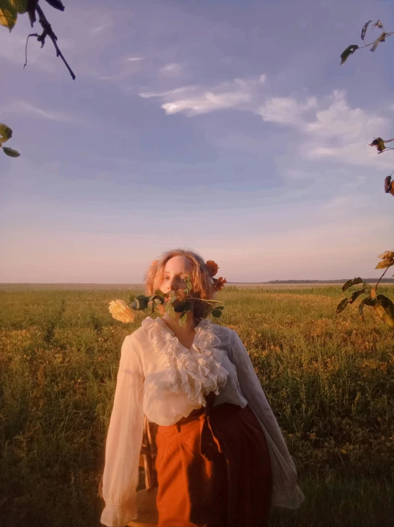 a woman stands in the middle of a field with wildflowers