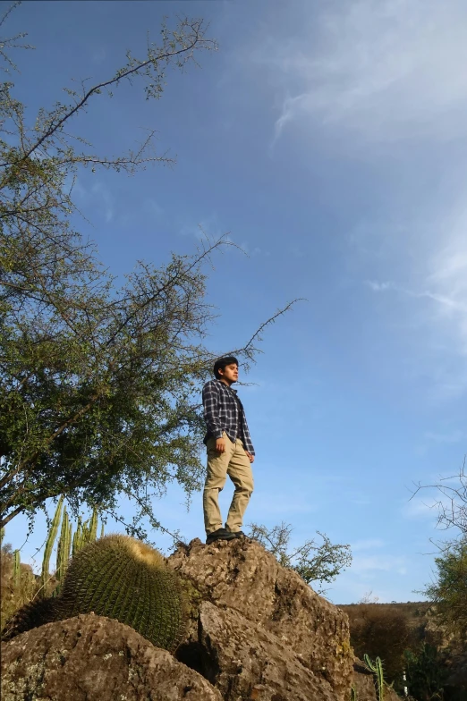 a man standing on top of a big rock with a rifle