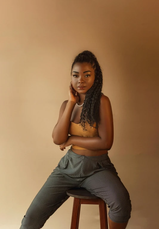 an african american female in a crop top posing on a stool