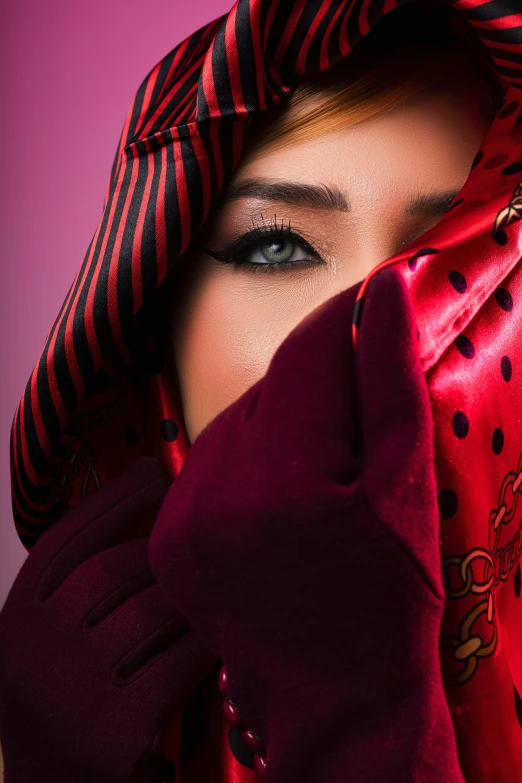 a woman's eyes are showing behind a red material