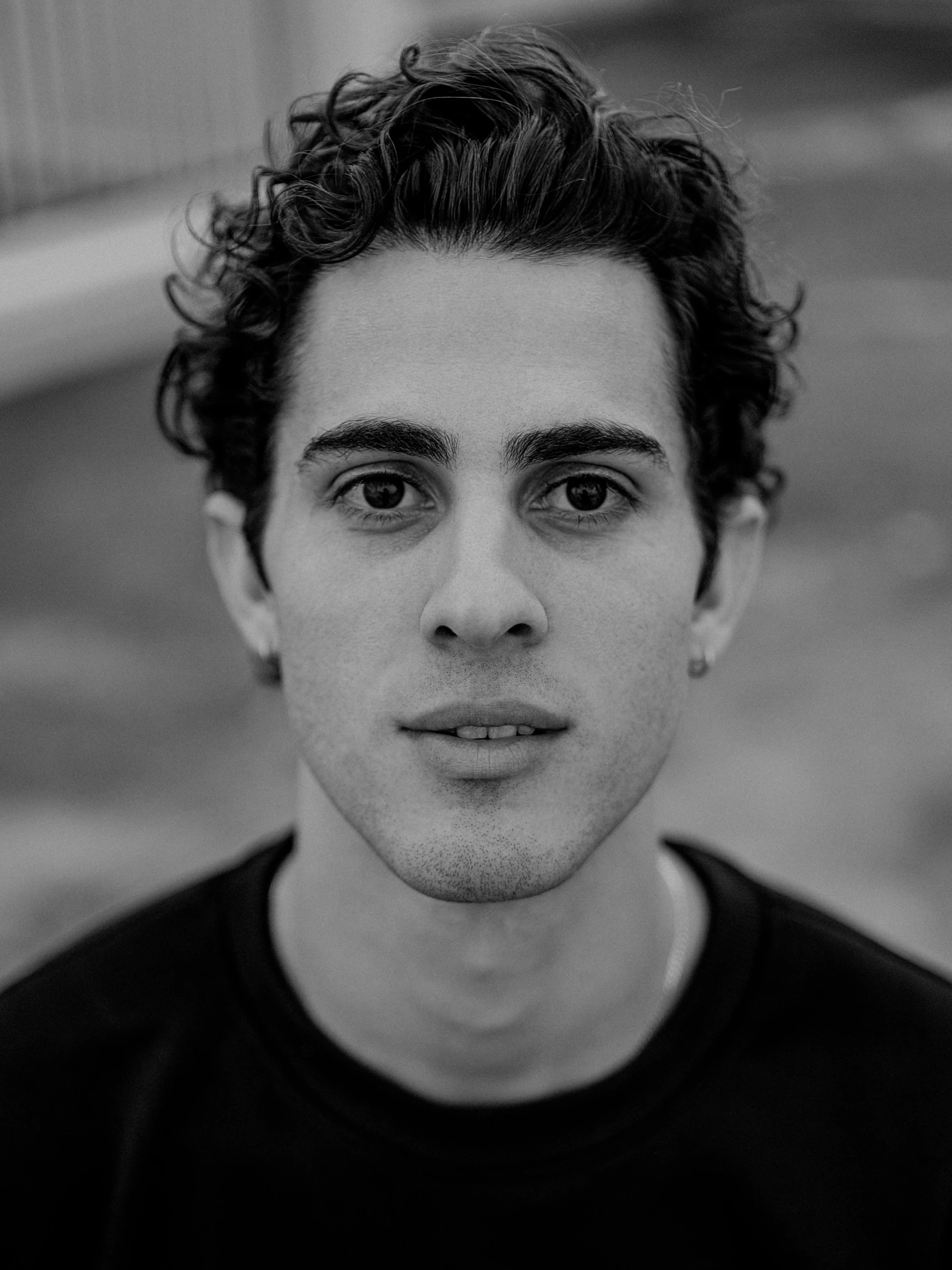 a young man standing in front of a wall looking straight ahead