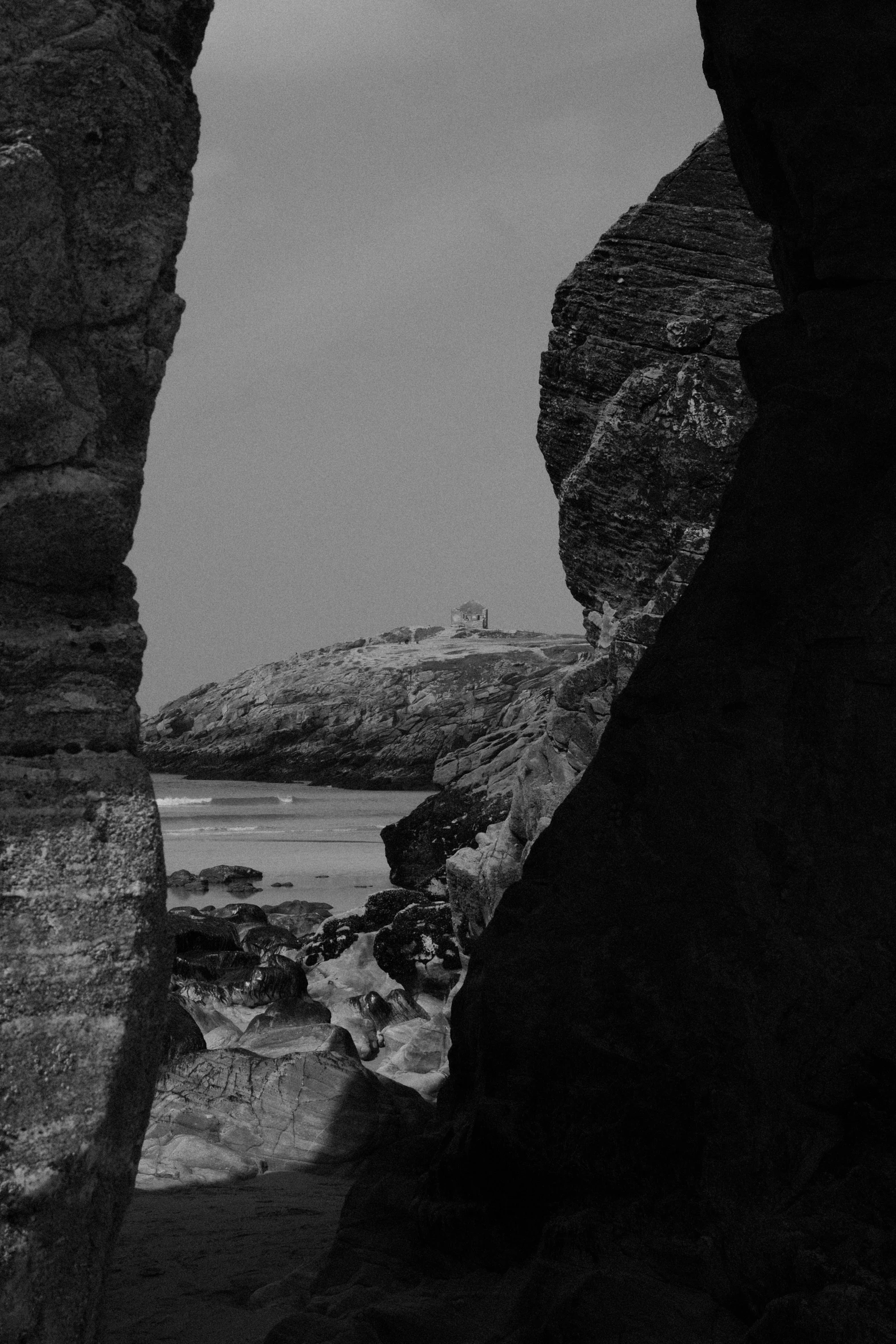 a man is standing at the edge of an arch looking at the ocean