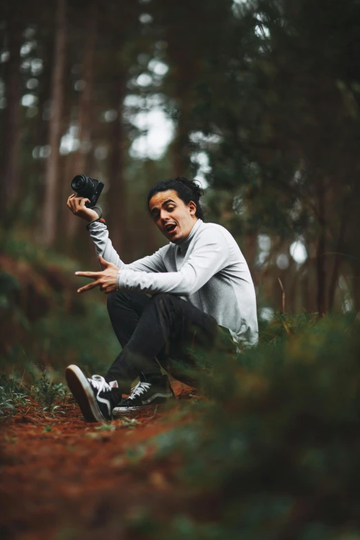 a man kneeling on the ground in a forest