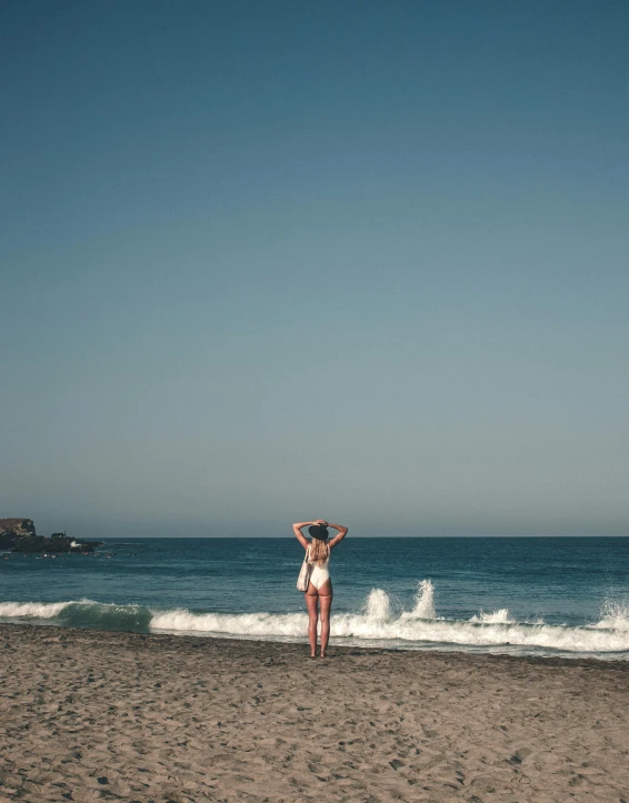 a woman in a white bikini stands on the beach