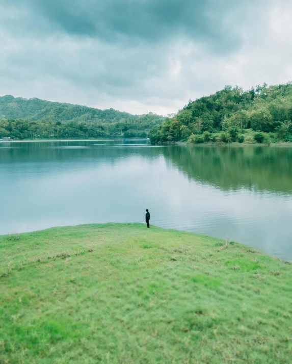 a man that is standing on some grass near water