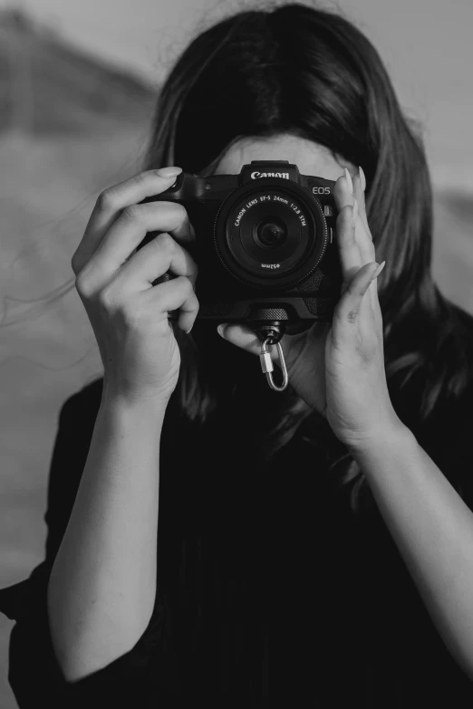 a woman holding a camera to her face while she is taking pictures