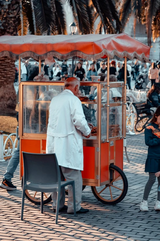 a child standing next to an orange and white cart