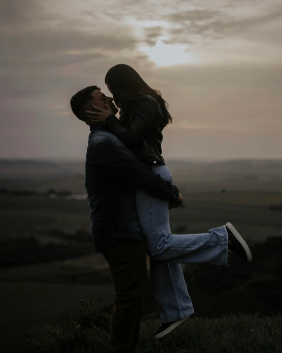 a couple that is in the grass under a cloudy sky