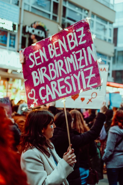 a woman holds a sign in front of a crowd