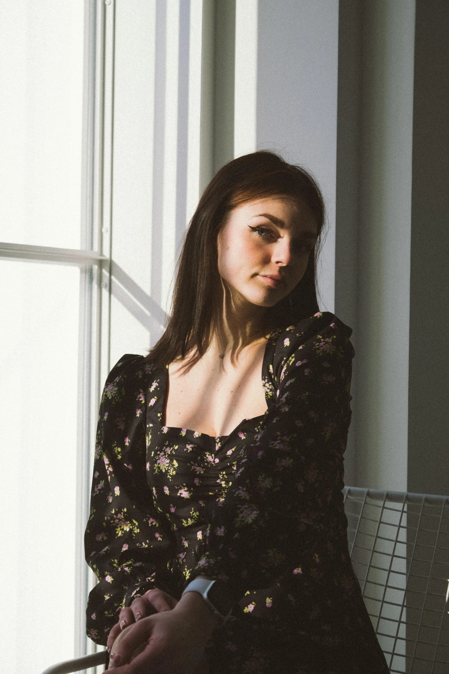 woman standing in front of an open window next to white wall