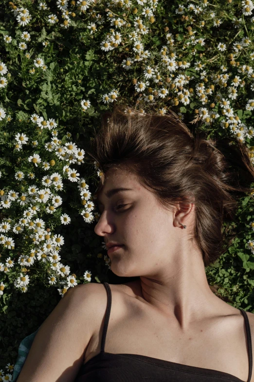 a woman lying in front of flowers in the sunshine