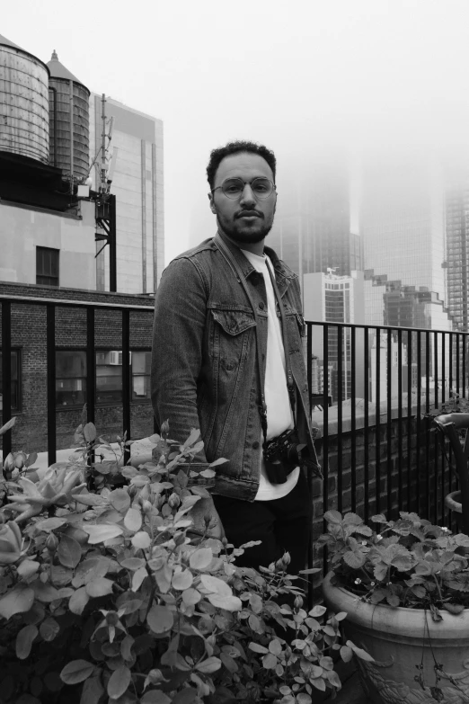 black and white pograph of man in jacket standing on railing