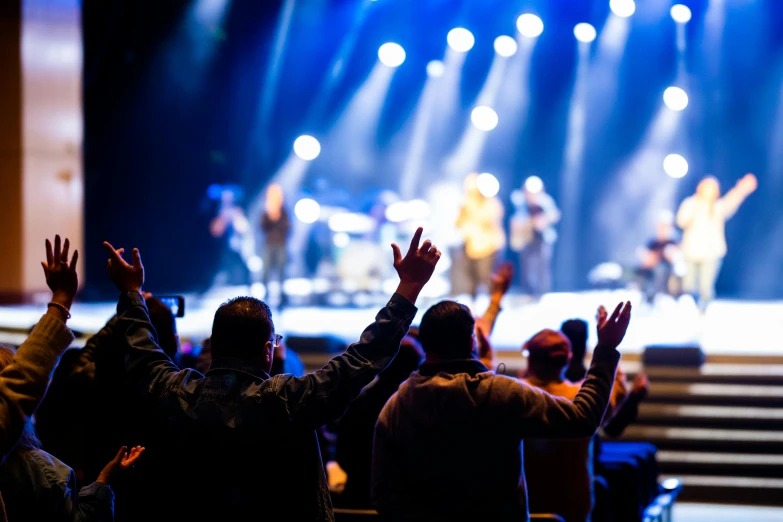 several people are clapping in front of an audience