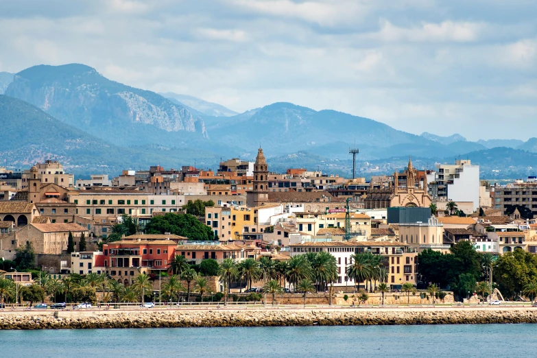 the town is next to a river and the mountain range is behind it