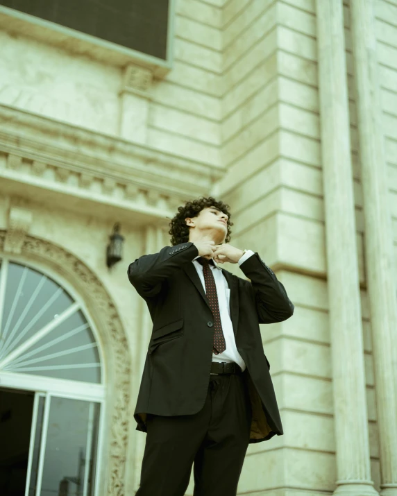 a person with a suit and tie standing in front of a building