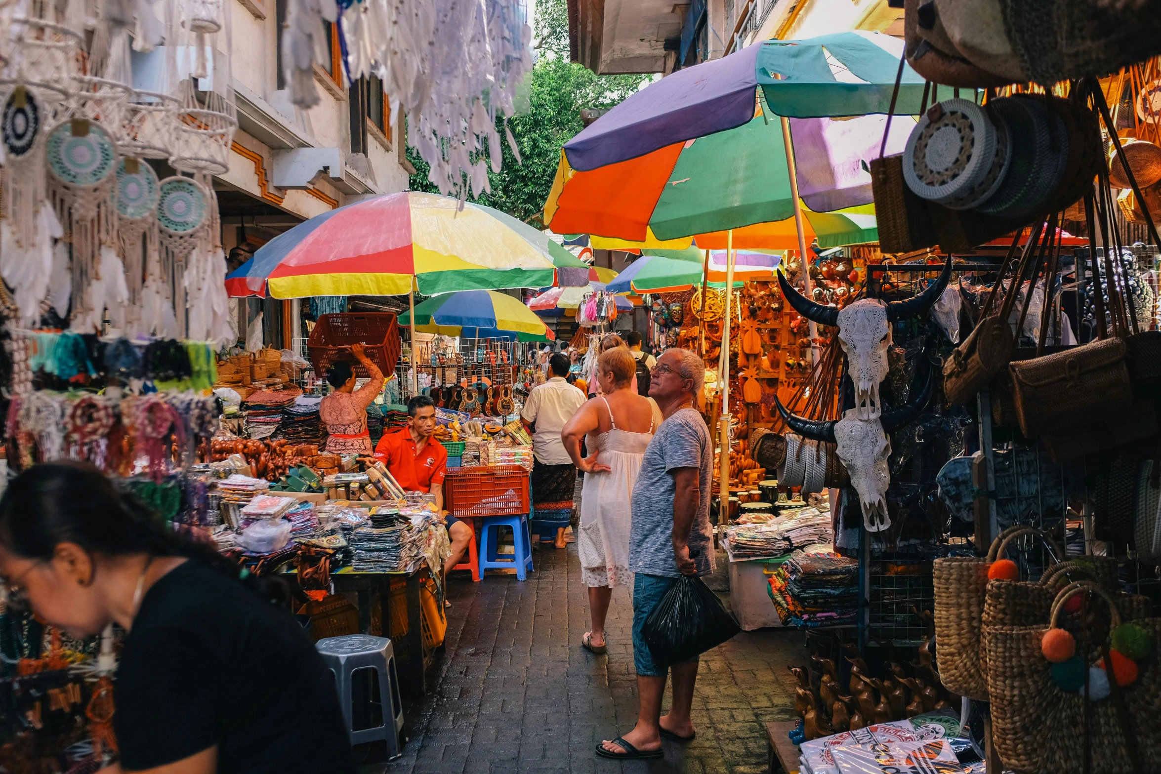 a crowded street market with multiple umbrellas on display