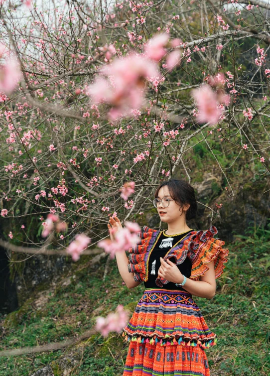 a woman is walking near pink blossoms in a park