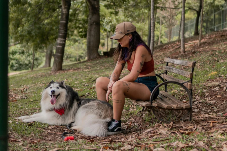 woman in baseball cap sitting next to an australian shepherd