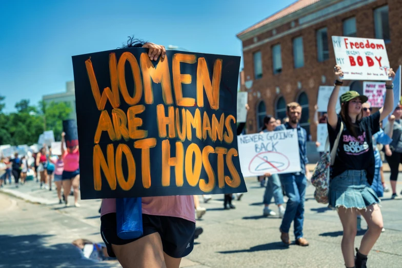 people on the sidewalk holding up signs in protest