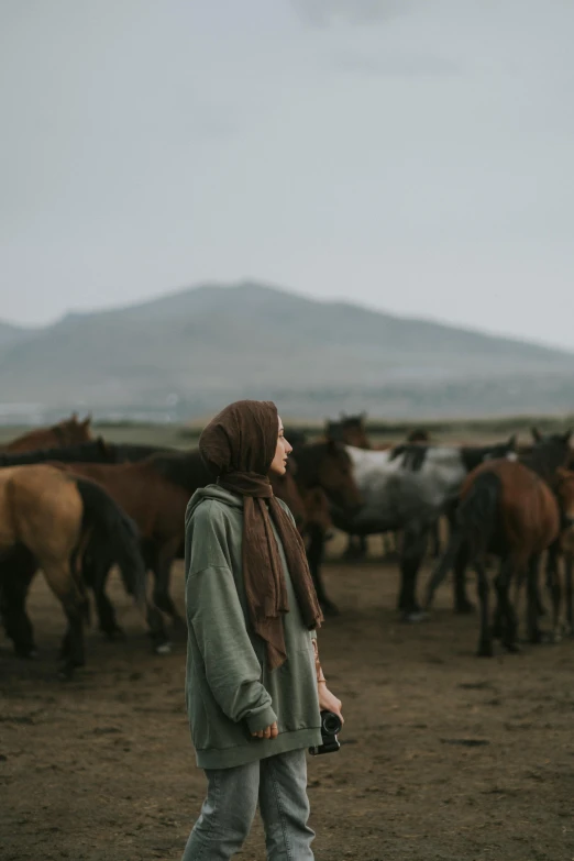 the woman is walking with the horses in the field