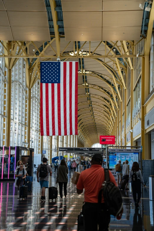 an air port with people walking by an american flag