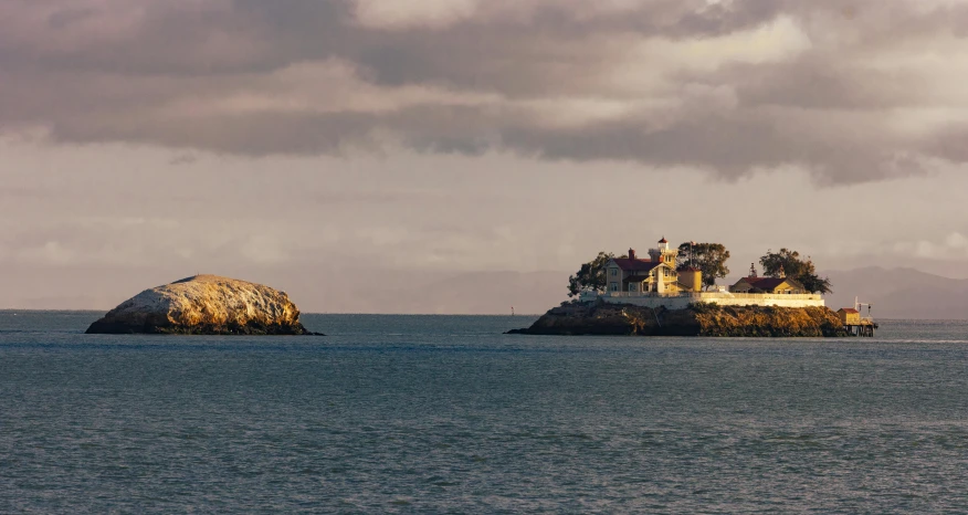 two rock formations in the water, one of them a house