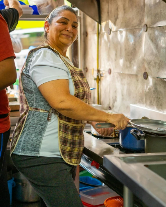 an elderly woman prepares food at a restaurant kitchen