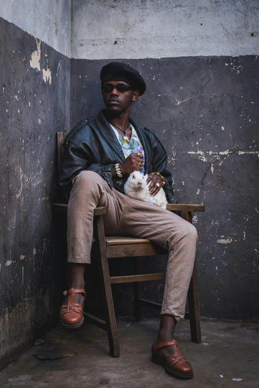 a man sitting in a wooden chair with a small cat