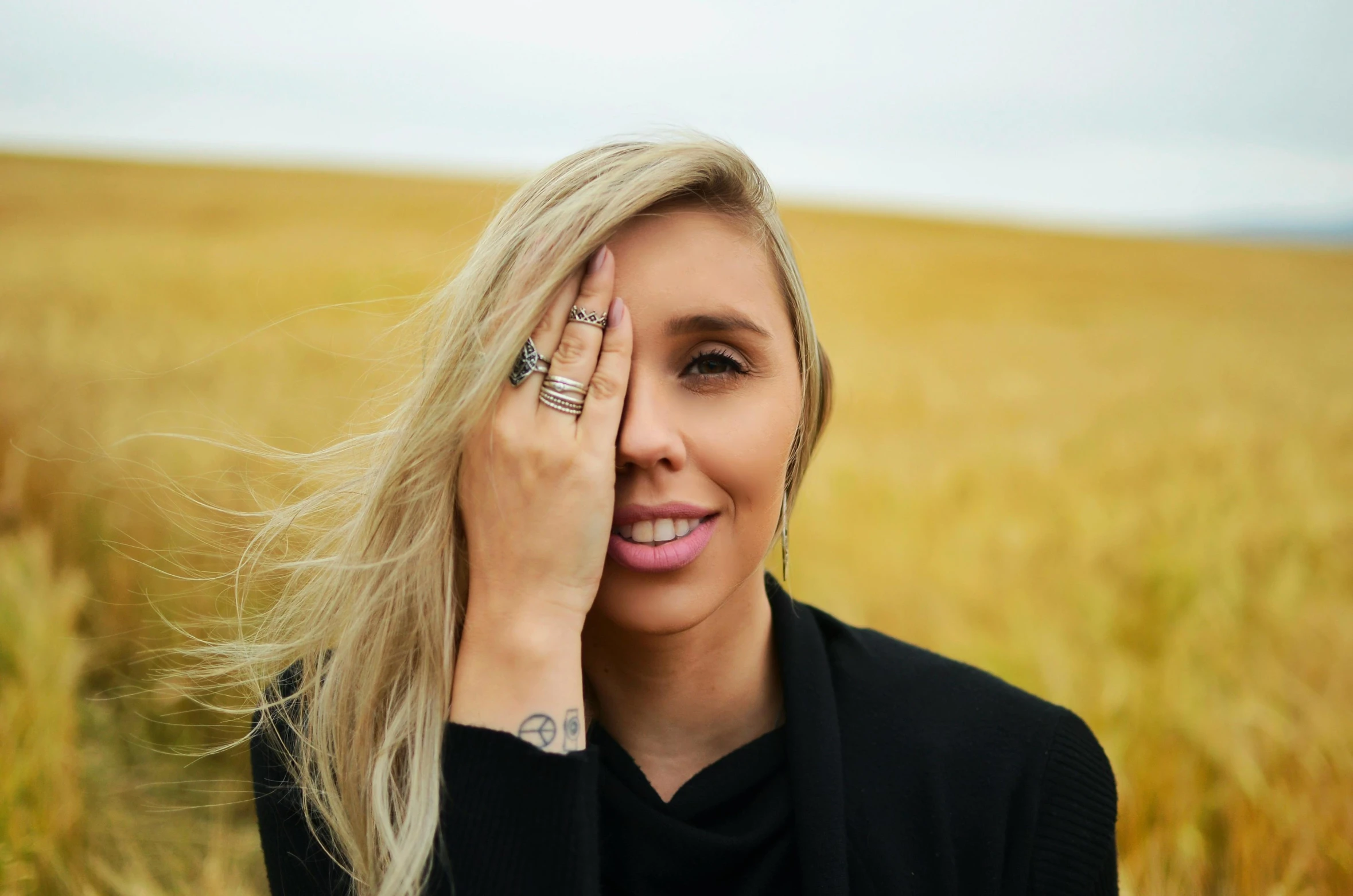 blond woman smiling and holding her hand to her face with the sun shining